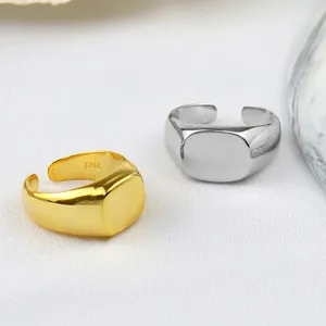 Close-up of minimalist square open signet rings in gold and silver, smooth geometric design.