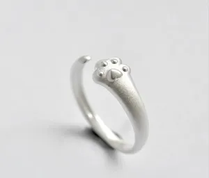 Nahaufnahme eines süßen silbernen Katzenpfoten-Rings, matte Oberfläche, feines Accessoire.