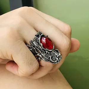 Λεπτομέρεια δαχτυλιδιού δράκου γοτθικού στυλ με ασημένια γλυπτική και κόκκινη πέτρα.