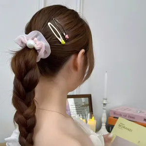 Vue détaillée d'élastique à cheveux perle rose et jolies pinces cœur pour femmes.