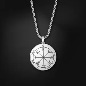 Primer plano del colgante de acero inoxidable con grabados de talismanes detallados y cadena.