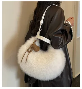 Gros plan sur le sac porté épaule duveteux blanc avec breloque cœur en tricot marron.
