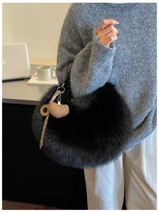 Gros plan sur le sac porté épaule duveteux noir avec joli charm en tricot en forme de cœur.