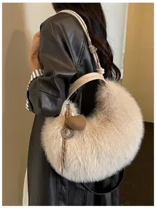 Détails du sac à bandoulière croissant duveteux montrant une fausse fourrure douce et un charm.