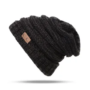 Close up detail view of the dark grey knitted beanie texture, soft fabric and leather logo patch.