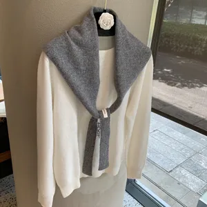 Detailed view of layered grey knit scarf shawl paired with white sweater, soft texture.