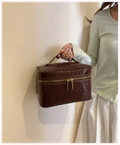 Braune Krokodilmuster Kosmetiktasche mit Griff und Goldreissverschluss fuer Make-up Aufbewahrung.