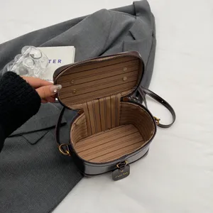 Élégant sac vanity rigide marron avec fermeture éclair supérieure et design de boîte.
