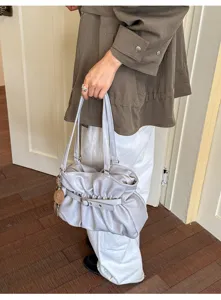 Gros plan détaillé du sac cabas plissé gris stylé avec sangle à boucle et accessoire.