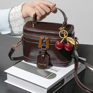 Sac à main vanity marron foncé chic avec charm cerise, sac bandoulière vintage élégant femme.