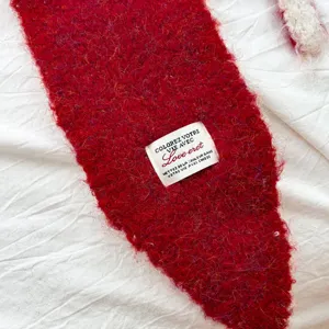 Roter flauschiger Strickschal Detailansicht mit weicher Wolle und eingenähtem Etikett.