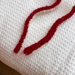 Detaillierte Nahaufnahme der weissen Waffelstrick Winter Schal Textur mit rotem Kordelzug.