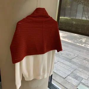 Chal de punto rojo sobre jersey blanco, proteccion para el cuello comoda en detalle.