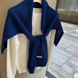 Detalle de chal bufanda de punto de lana azul con textura suave y estilo de capas cálido.