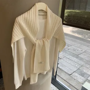 Vista cercana detallada de bufanda de lana blanca y jersey, estilo de invierno acogedor.