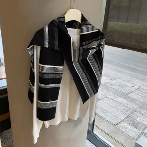 Detailaufnahme einer schicken schwarz-weißen Strickstola mit weißem Oberteil, kuschelige Lagenmode.