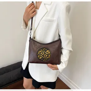 Vue détaillée du sac bandoulière en cuir marron avec motif gaufré vintage et bandoulière.