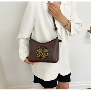 Gros plan sur le sac à bandoulière en cuir véritable doté d'un motif circulaire gaufré.