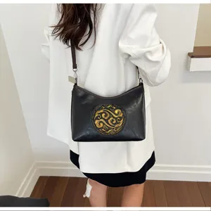 Vue détaillée du sac à bandoulière en cuir véritable pour femmes avec motif chinois doré.