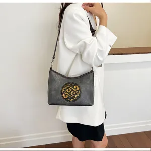 Vue détaillée d'un sac bandoulière en cuir gris avec un motif gaufré doré de style chinois.