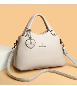 Vue détaillée du sac à main beige pour femme en cuir texturé avec poignée et charm métallique.
