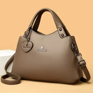 Détail de sac à main en cuir marron montrant la texture, la poignée et les accessoires.
