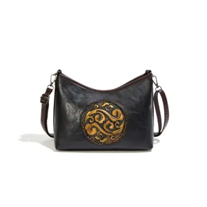 Sac à bandoulière en cuir véritable style chinois pour femme avec motif médaillon doré.