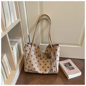 Vue détaillée du sac fourre-tout élégant à pois avec de longues poignées et breloque.
