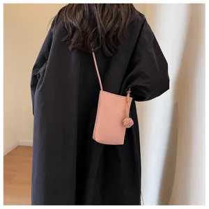 Vue détaillée du mini sac bandoulière minimaliste en cuir souple rose avec détail de nœud.