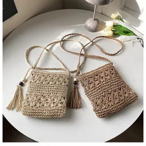 Woven straw crossbody bag detail showing intricate crochet texture, fringe tassel and wood beads.