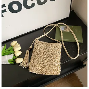 Handmade straw crossbody bag detail, woven pattern with cute tassel and slender shoulder strap.