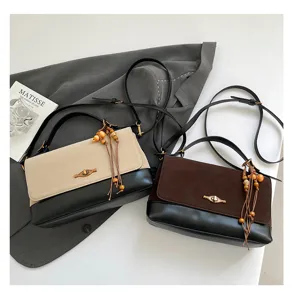 Borsa a tracolla retrò bicolore con nappa di perline di legno e chiusura in metallo.