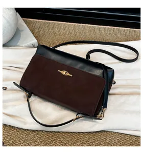 Vista dettagliata di una elegante borsa a tracolla da donna nera e marrone con serratura.
