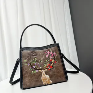 Detail shot of brown faux leather crossbody bag featuring exquisite floral deer embroidery design.