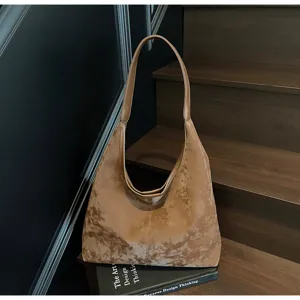 Vue détaillée du sac hobo en velours marron texturé avec une courbe élégante et douce.