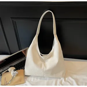 Vue détaillée du sac porté épaule souple blanc stylisé dans une scène de navetteur chic avec PC.