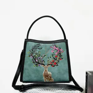 Detailed view of the embroidered sika deer and floral pattern on the green leather bag.