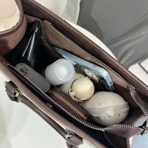 Vista dettagliata dell'interno della grande borsa marrone con vari scomparti pratici e tasche.