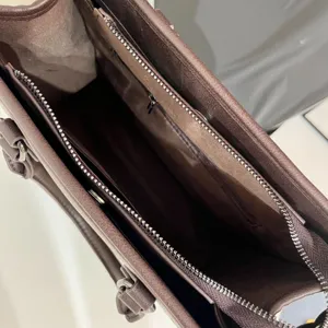 Dettaglio interno della borsa tote in pelle marrone con cerniere e scomparti multipli.