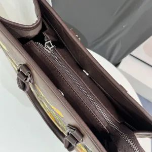 Dettaglio ravvicinato della borsa tote in pelle marrone scuro con zip e ricamo elegante.