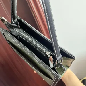 Dark green women handbag detail showing contrast stitching and zipper for daily commute.