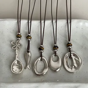 Detailed close-up of stylish Maillard necklaces with silver pendants and tiger eye beads.