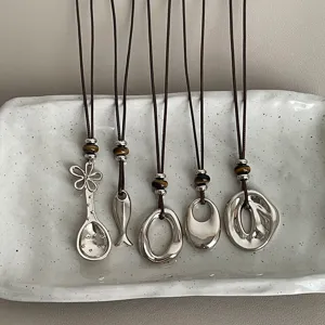 Detailed view of five unique silver pendant necklaces with tiger's eye beads and brown cords.