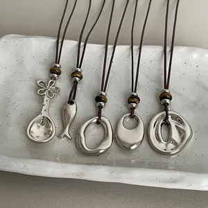 Close-up detail shot of unique metal pendant necklaces featuring tiger eye beads and cords.