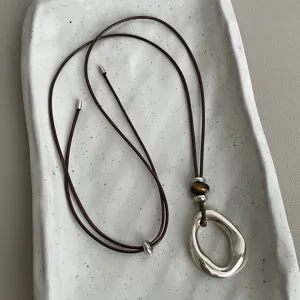 Chic Maillard style adjustable brown cord necklace with irregular metal oval pendant and tiger's eye.