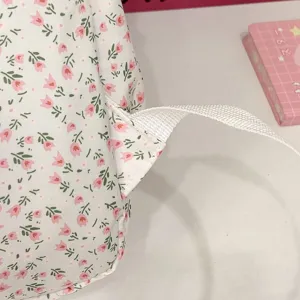 Gedetailleerd uitzicht op een schattige studentenrugzak met roze tulpenprint en band.