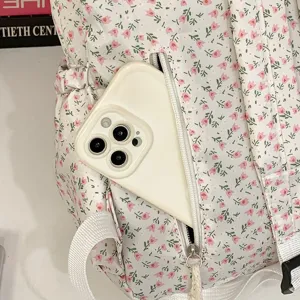 Detailopname van het voorste ritvak van de bloemrijke rugzak met smartphone erin.