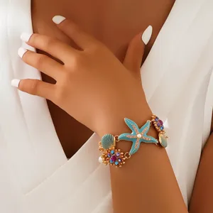 Nahaufnahme des ozeaninspirierten Seestern und Muschel Armband Details mit Kristallen.