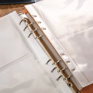 Close-up detail of binder photo album with transparent pockets and metal rings for DIY scrapbook.