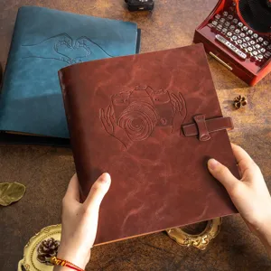 Detailed view of handmade vintage leather DIY photo albums with embossed camera and hand heart patterns.